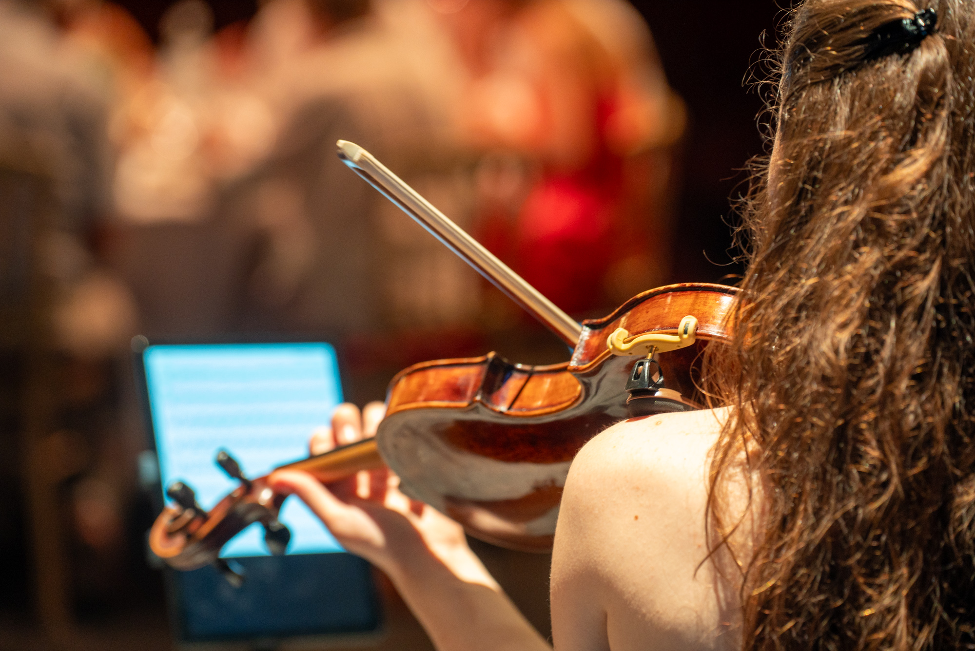 Violiste van achteren gezien, met bladmuziek op een tablet